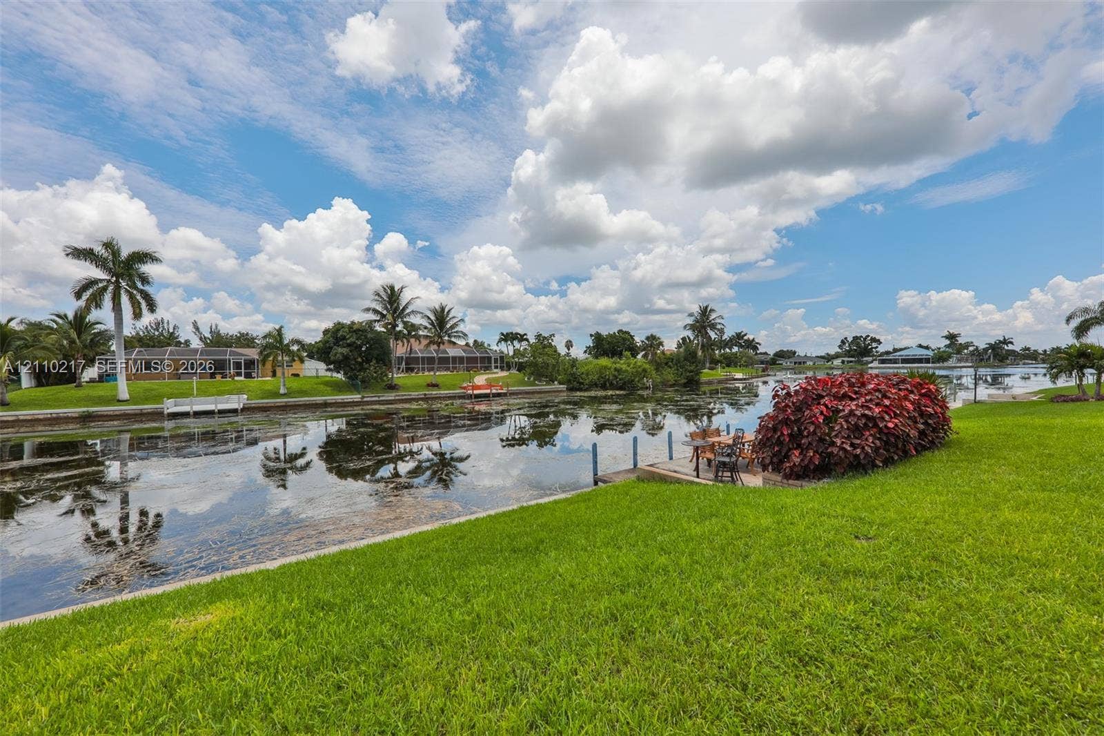 503 SW 17 Street, Cape Coral, FL 33990 Waterfront lot featuring a manicured lawn, stone bulkhead, and integrated dock