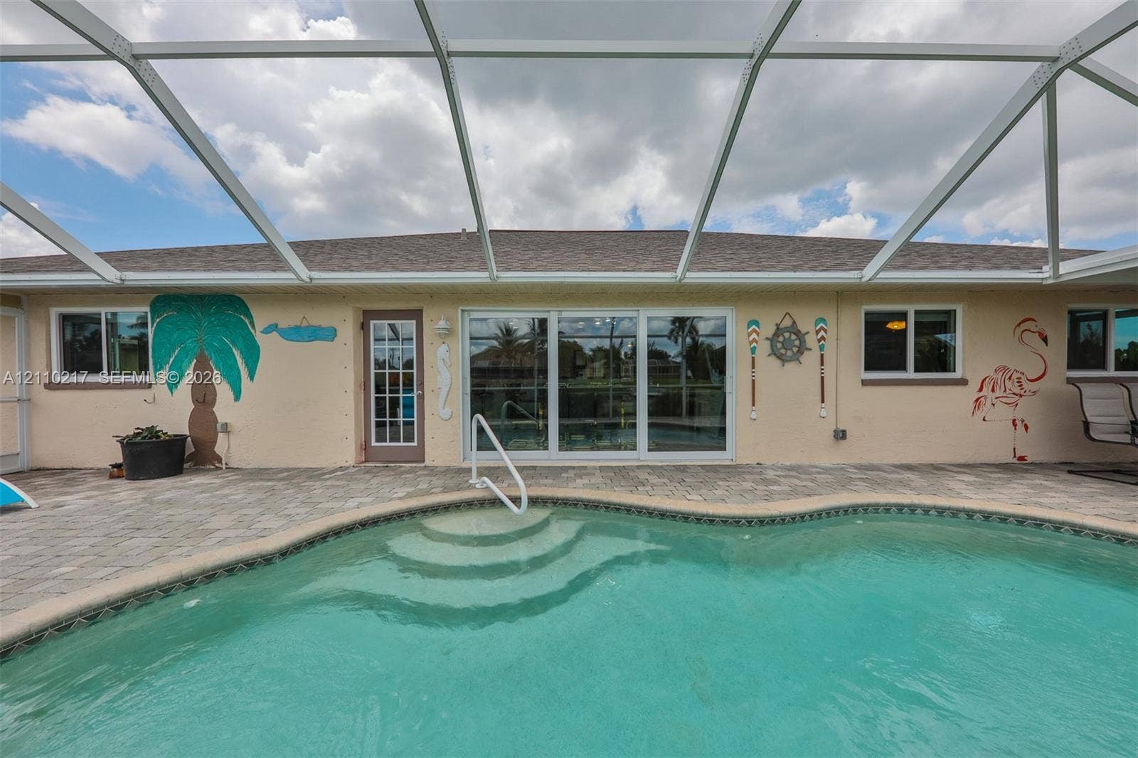 503 SW 17 Street, Cape Coral, FL 33990 Screen-enclosed pool area featuring a paver patio, integrated pool steps, and sliding glass door access
