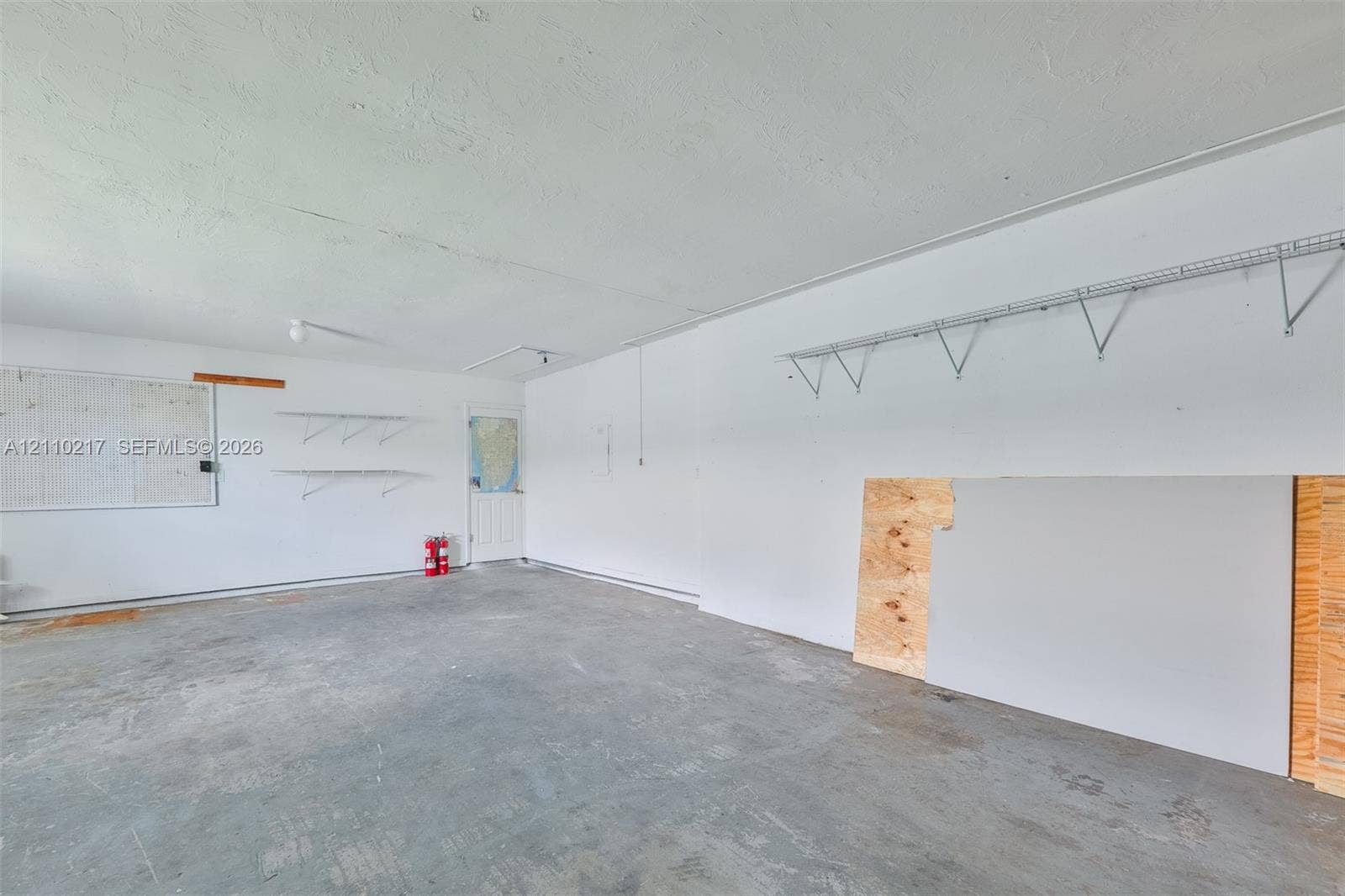 503 SW 17 Street, Cape Coral, FL 33990 Garage interior featuring finished walls, concrete flooring, and installed wire shelving units
