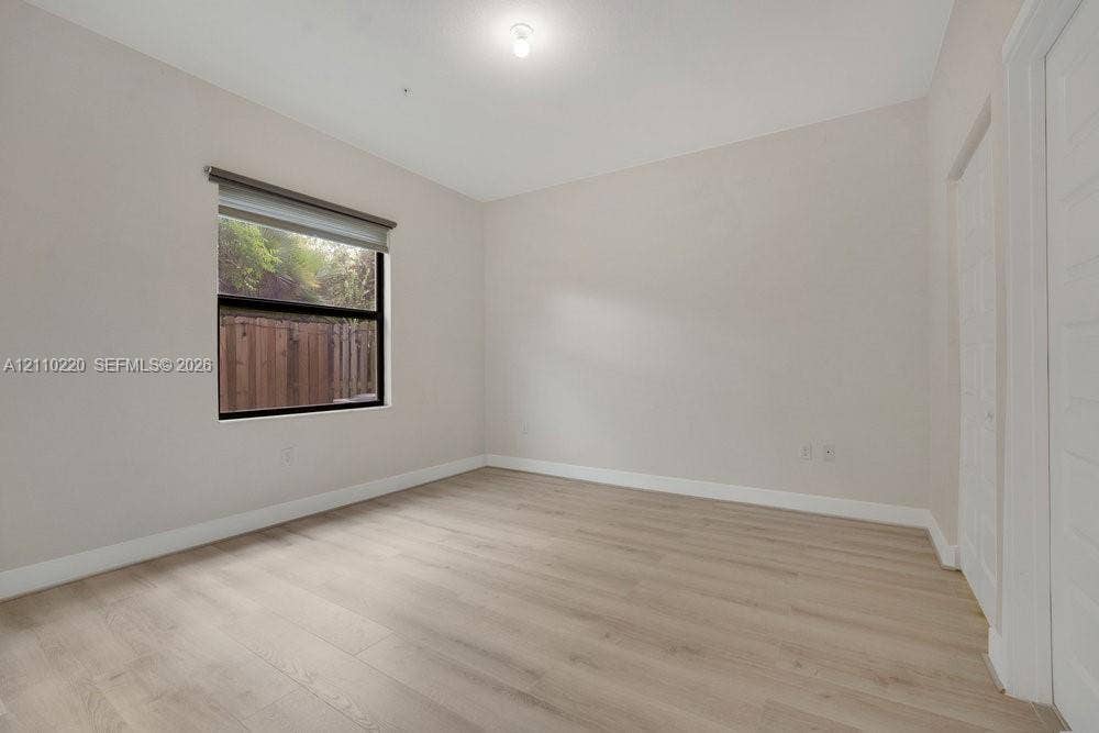 Neutral wall finishes, wood-finish flooring, recessed ceiling lighting, a single-pane window with a roller shade, and paneled closet doors