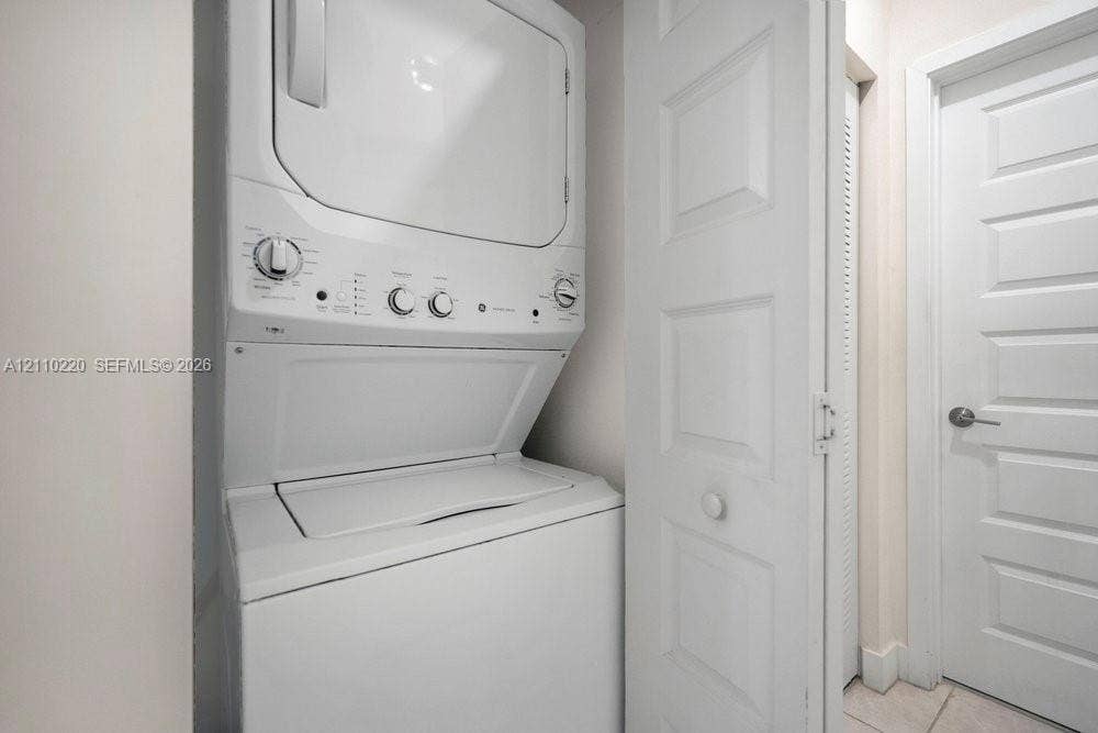 Stacked washer and dryer unit, louvered bi-fold closet doors, and solid-core paneled interior door