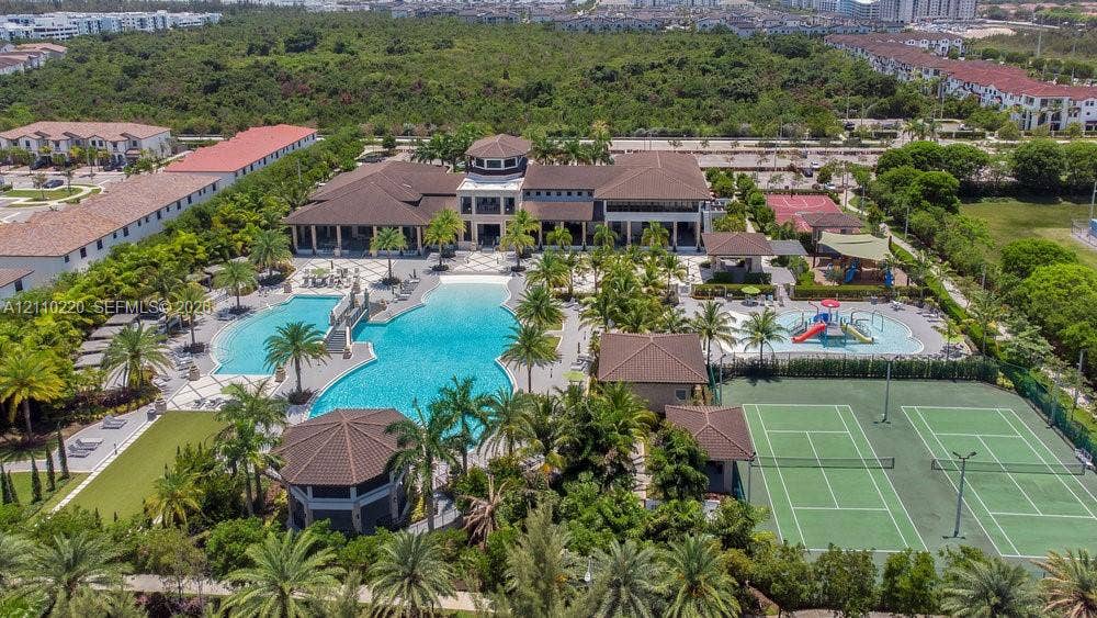 Community recreation complex featuring a large swimming pool, multi-use tennis courts, dedicated water play area, and covered structural pavilions