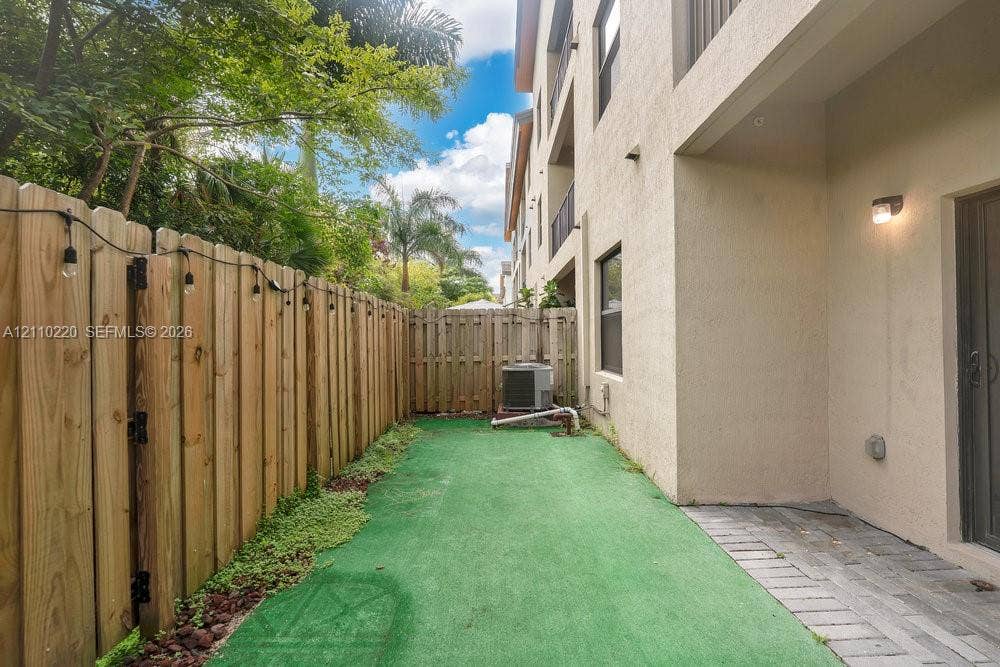Private outdoor space featuring a wood fence, concrete paver patio, and synthetic grass ground cover
