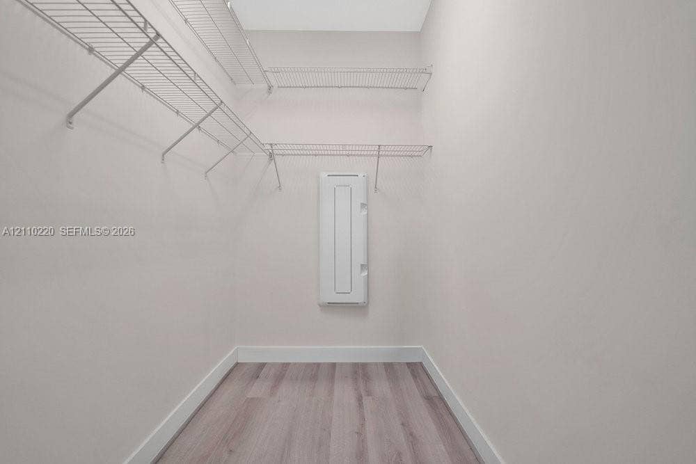 Storage space featuring tiered wire shelving and wood-finish flooring