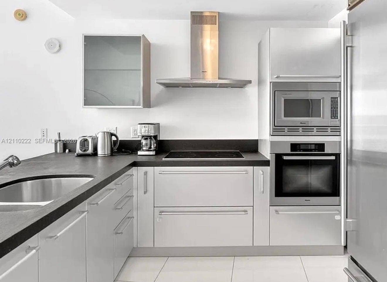 18201 Collins Avenue, #2008, Sunny Isles Beach, Sunny Isles Beach, FL 33160 Kitchen featuring sleek white cabinetry, matte black countertops, stainless steel range hood, built-in wall oven and microwave, and large-format tile flooring