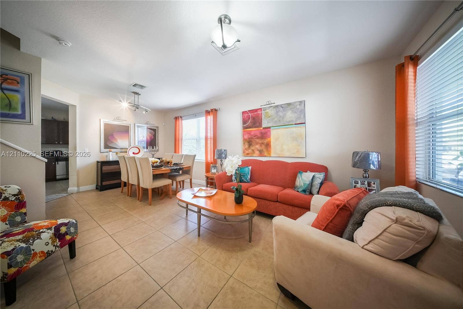 Open-concept interior featuring neutral tile flooring, multi-directional track lighting, and a semi-flush mount fixture