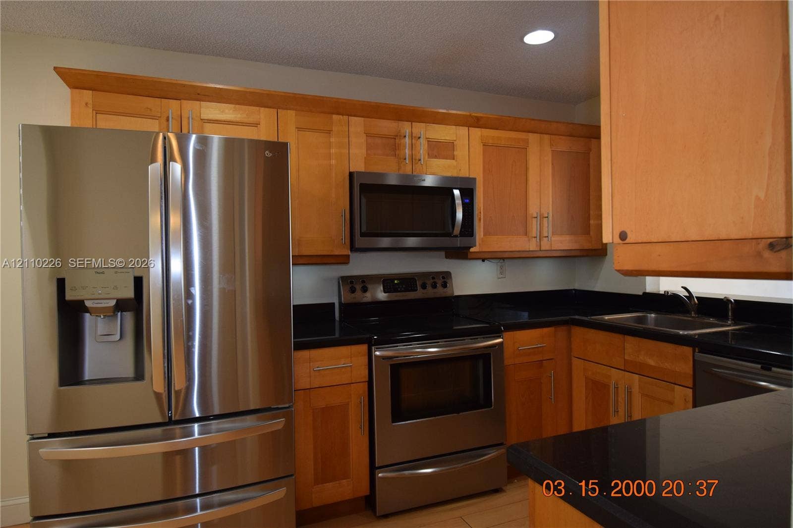 Kitchen featuring wood-finish cabinetry, dark solid-surface countertops, stainless steel appliances, and recessed lighting