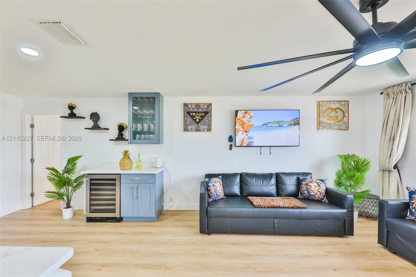 450 Bayshore Drive, Cape Coral, FL 33904 Built-in wet bar featuring stone-finish countertops, glass-front cabinetry, and an integrated beverage refrigerator, complemented by wood-finish flooring and a multi-blade ceiling fan with integrated LED lighting