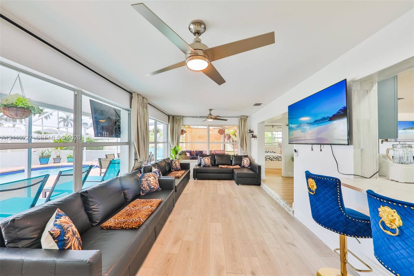 450 Bayshore Drive, Cape Coral, FL 33904 Light-filled interior featuring wood-finish flooring, dual ceiling fans, and a pass-through breakfast bar