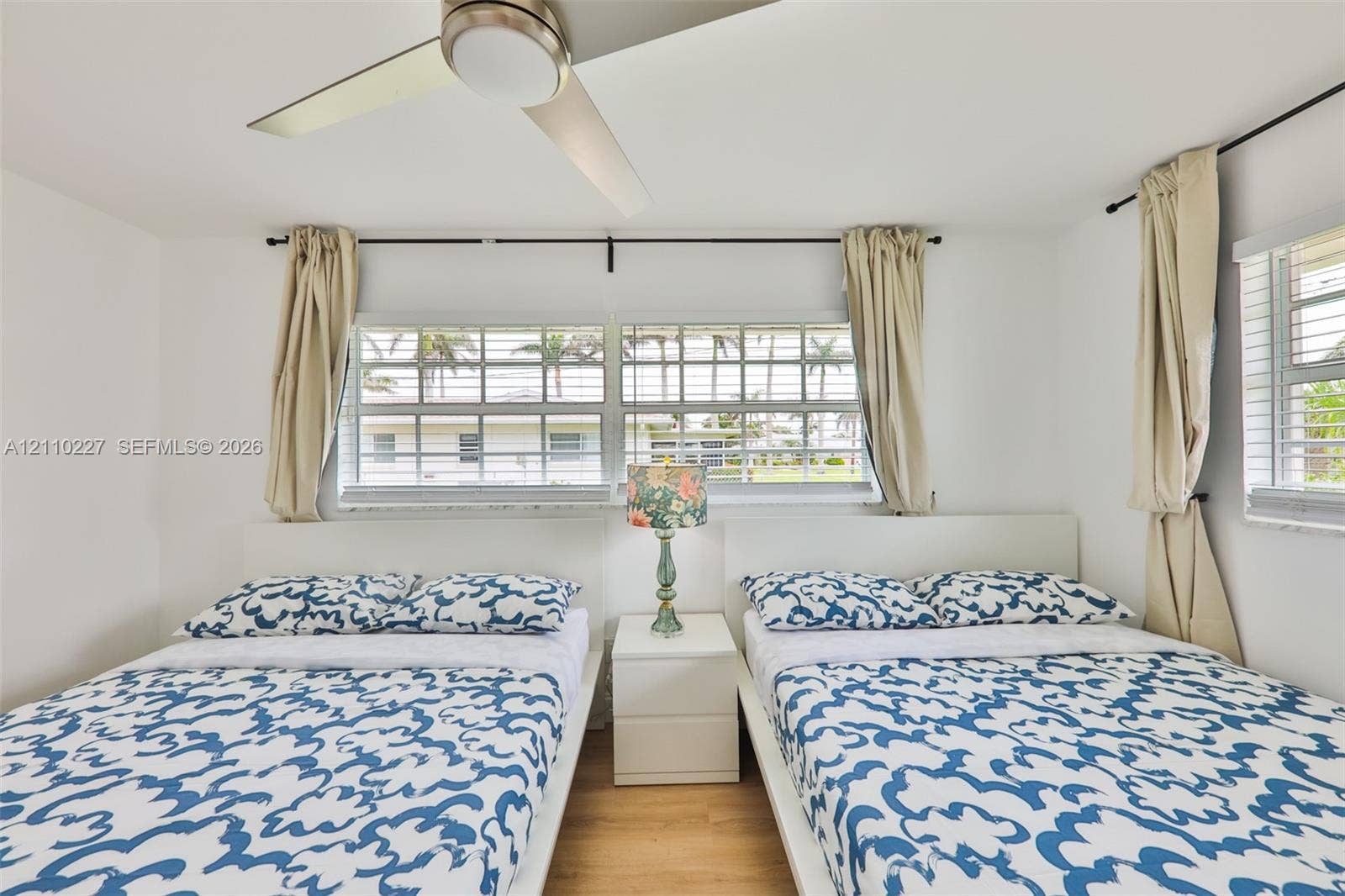 450 Bayshore Drive, Cape Coral, FL 33904 Room featuring wood-finish flooring, a contemporary ceiling fan with integrated lighting, and multiple horizontal sliding windows with metal rod hardware