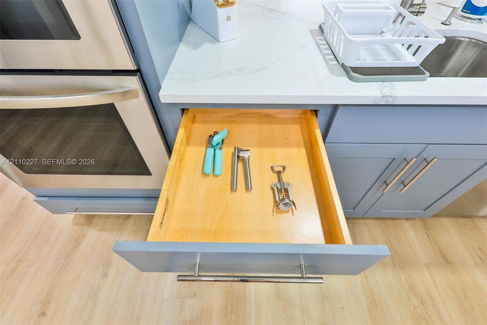 450 Bayshore Drive, Cape Coral, FL 33904 Soft-close solid wood drawer with dovetail joinery, light-toned finish, stainless steel bar pull, quartz countertop, and integrated stainless steel wall oven