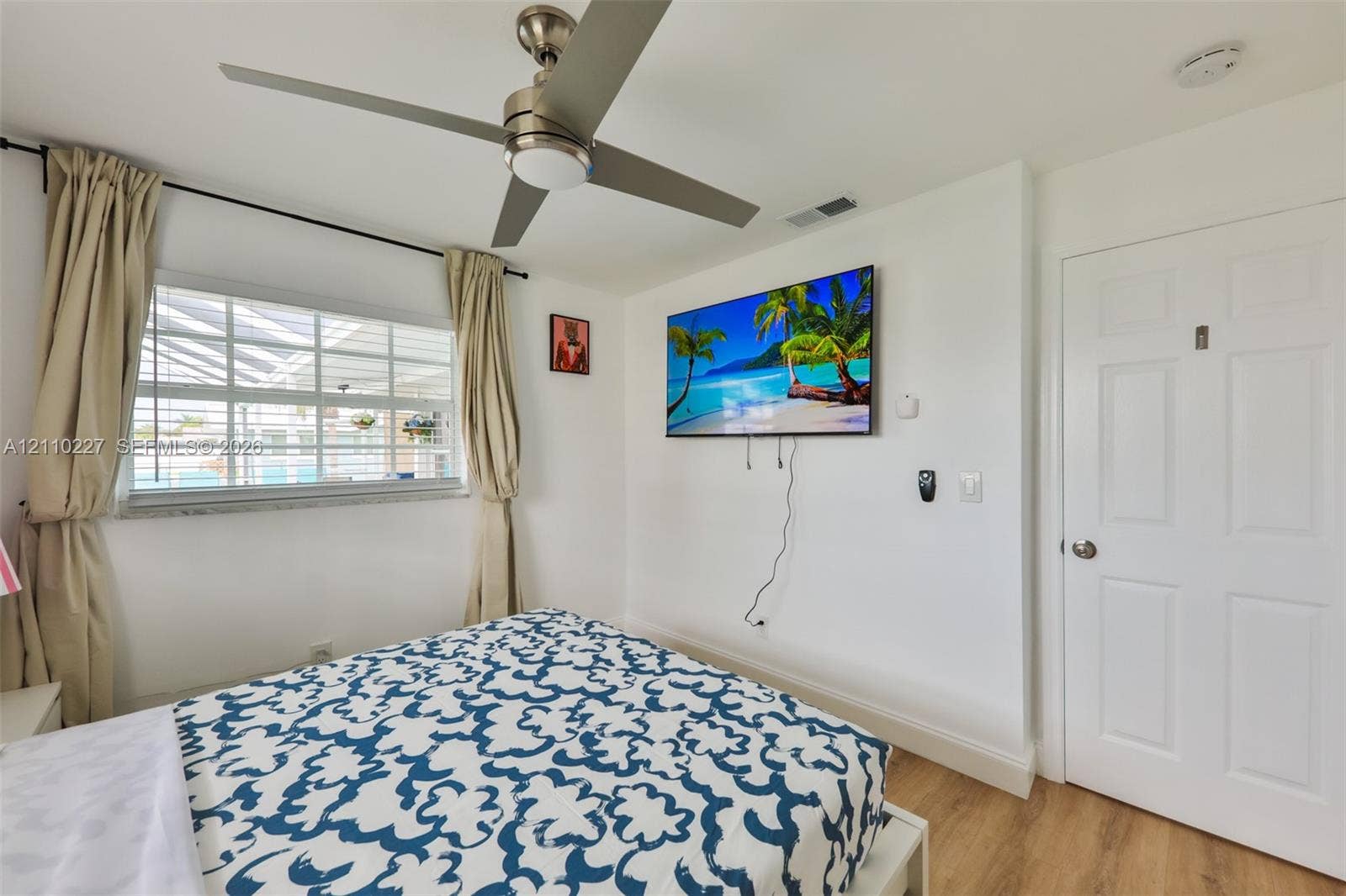 450 Bayshore Drive, Cape Coral, FL 33904 Neutral interior featuring wood-finish flooring, a contemporary brushed-metal ceiling fan, multi-pane window, and a six-panel door