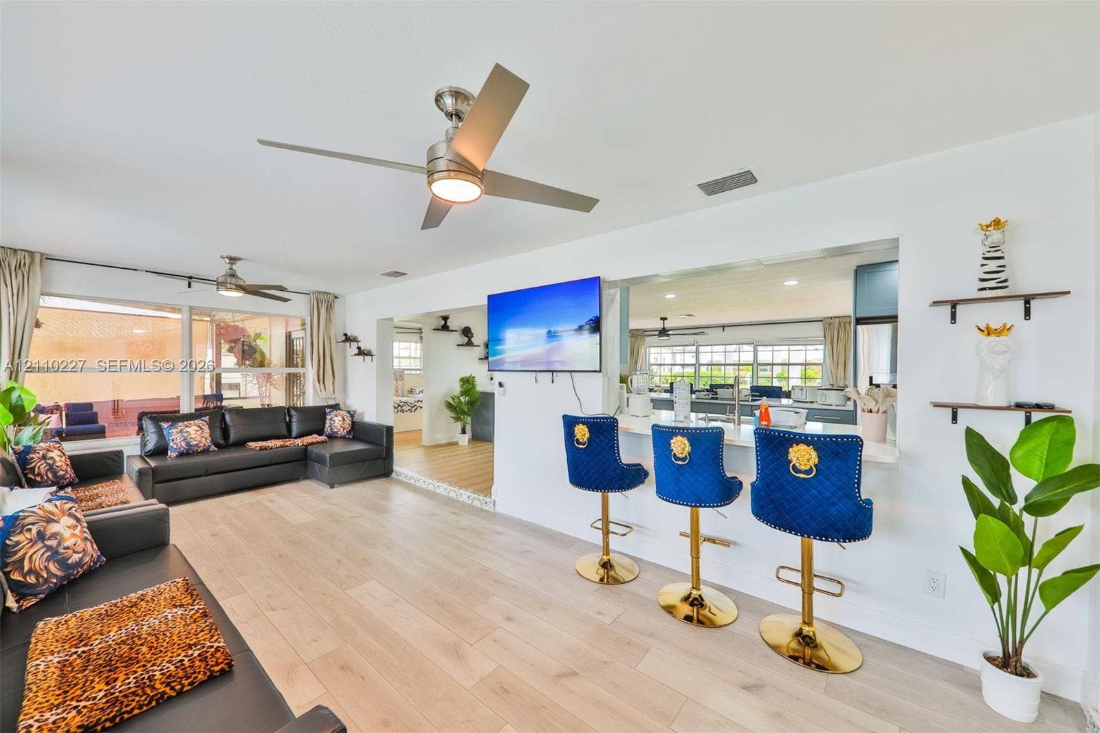 450 Bayshore Drive, Cape Coral, FL 33904 Open-concept interior featuring wood-finish flooring, brushed metal ceiling fans, and a breakfast bar with stone-surface counters