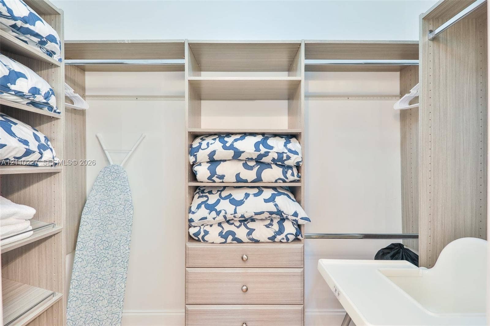 450 Bayshore Drive, Cape Coral, FL 33904 Custom walk-in closet featuring light-toned wood-finish cabinetry, adjustable open shelving, integrated hanging rods, and a three-drawer built-in chest