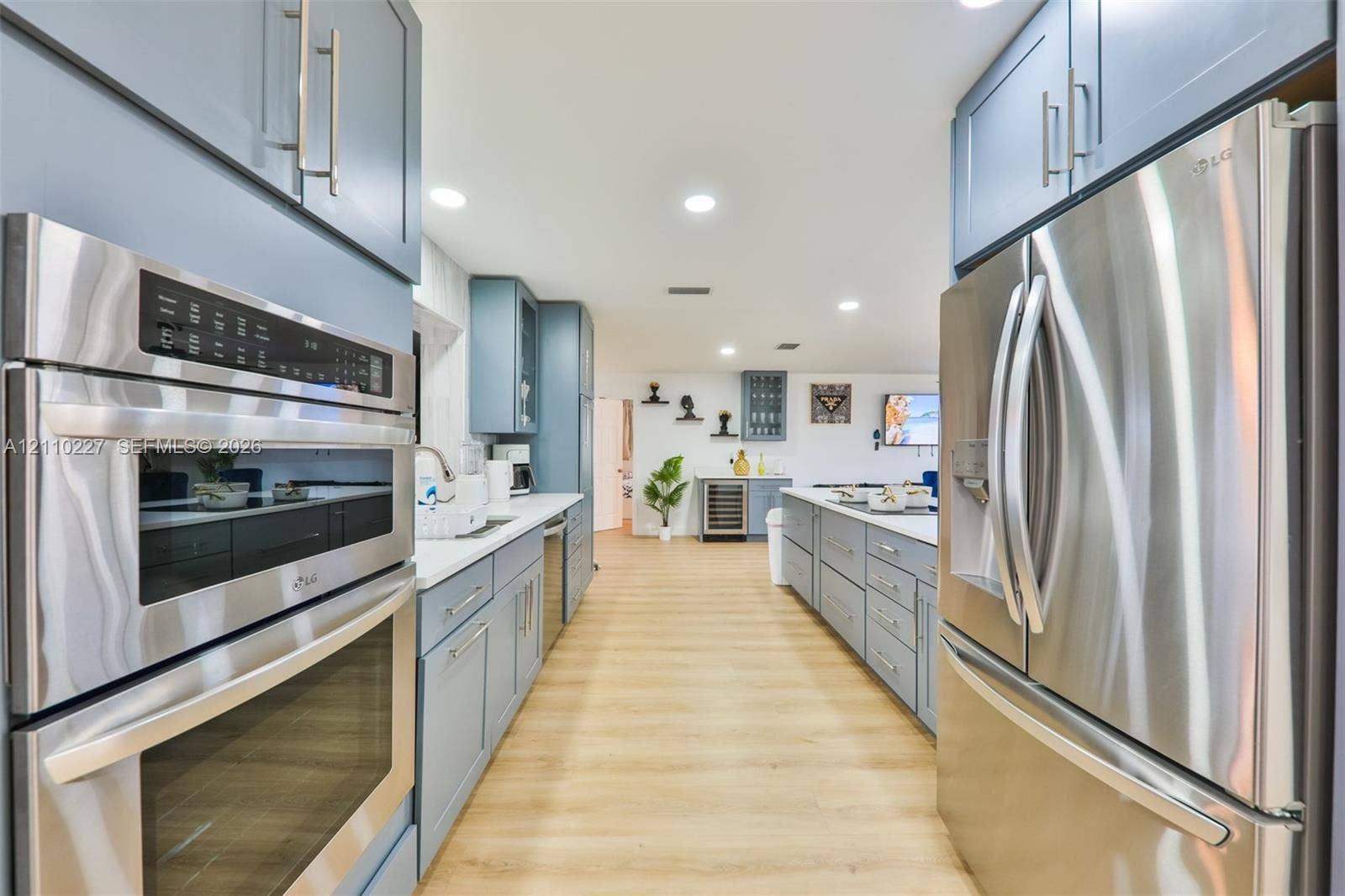 450 Bayshore Drive, Cape Coral, FL 33904 Kitchen featuring wood-finish flooring, stainless steel appliances, dual wall ovens, blue shaker-style cabinetry, and recessed lighting