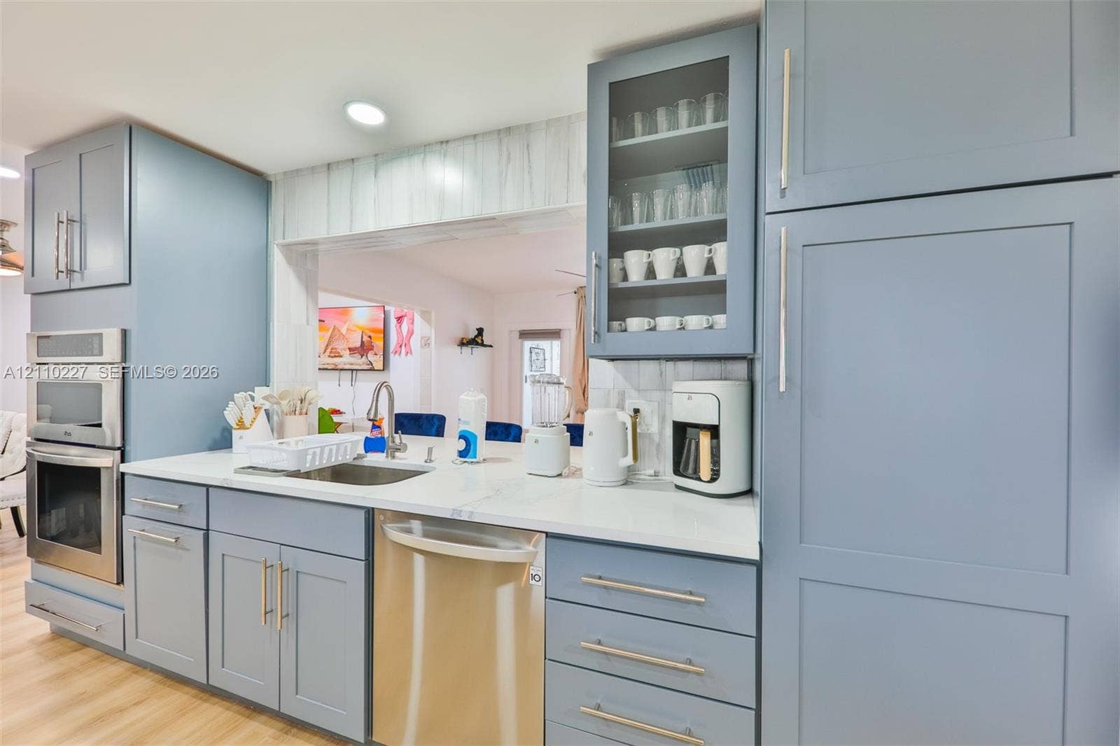 450 Bayshore Drive, Cape Coral, FL 33904 Kitchen featuring blue shaker-style cabinetry, white countertops, stainless steel appliances, and a glass-paneled upper cabinet