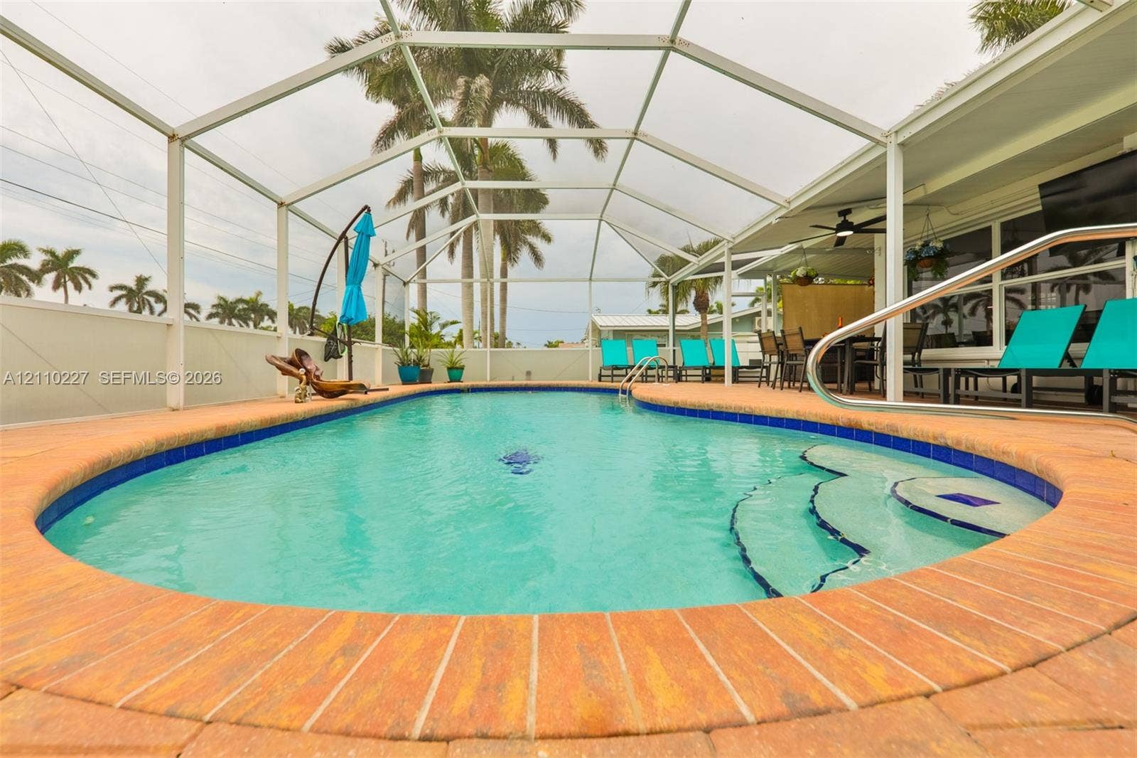 450 Bayshore Drive, Cape Coral, FL 33904 Screened-in outdoor area featuring a swimming pool with built-in steps, brick paver coping, and a covered lanai