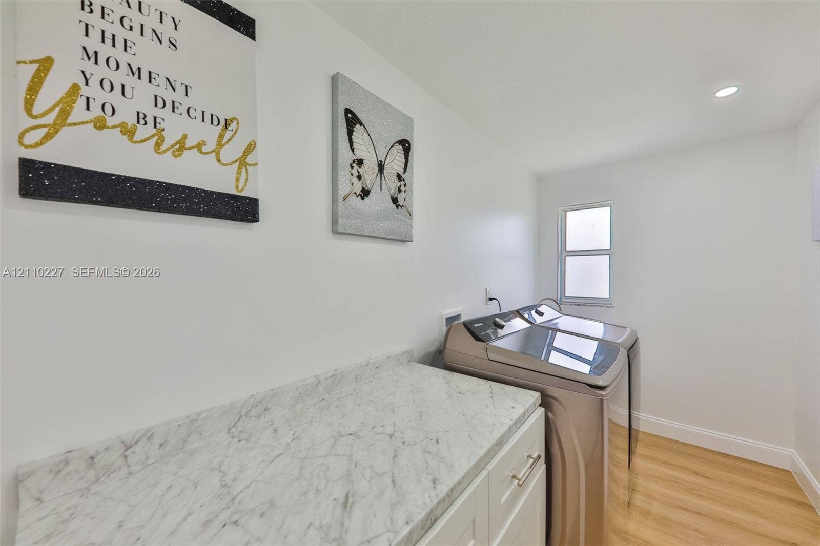 450 Bayshore Drive, Cape Coral, FL 33904 Laundry area featuring white cabinetry, light-toned stone-finish countertop with matching backsplash, wood-finish flooring, and recessed ceiling lighting