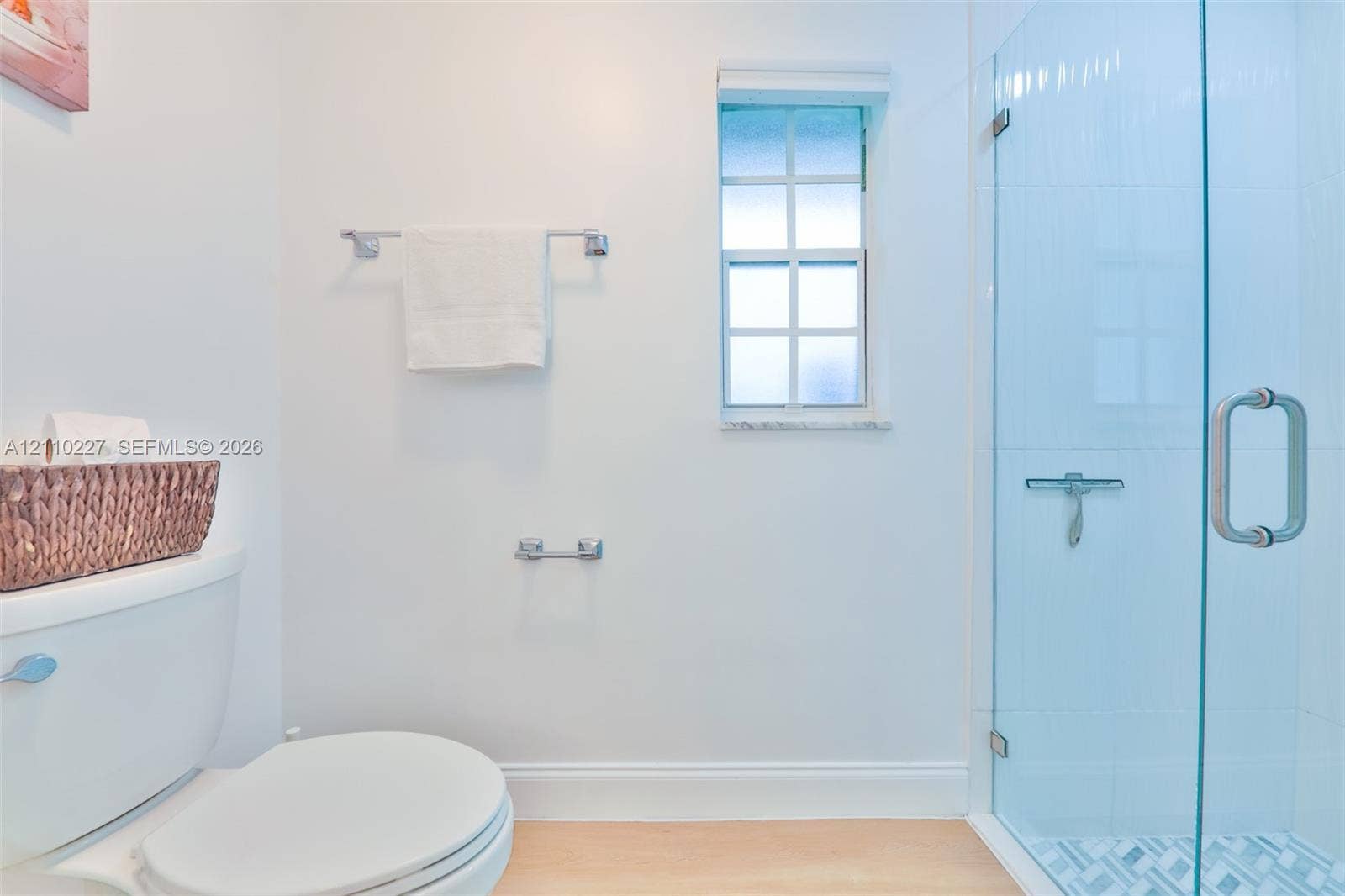 450 Bayshore Drive, Cape Coral, FL 33904 Shower enclosure with a frameless glass door, light-toned wood-finish flooring, and a window with muntins