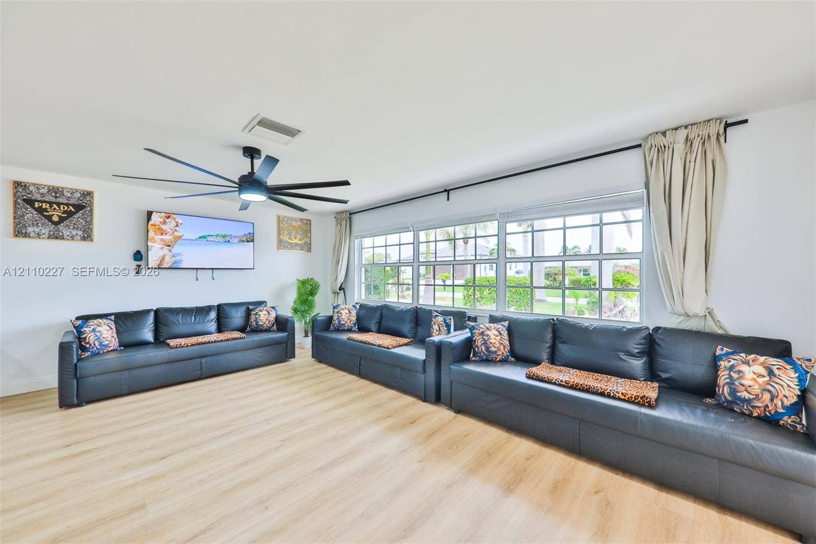 450 Bayshore Drive, Cape Coral, FL 33904 Living area featuring wood-finish flooring, a contemporary multi-blade ceiling fan, and expansive windows with grid-pattern muntins