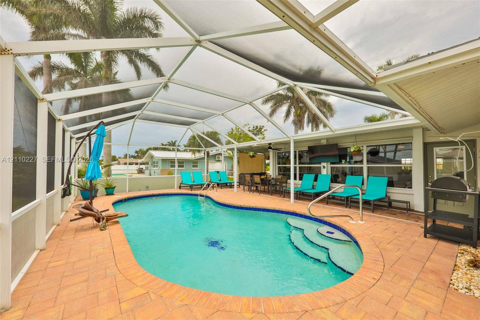 450 Bayshore Drive, Cape Coral, FL 33904 Screened-in patio featuring a paver pool deck and in-ground swimming pool with integrated stair entry
