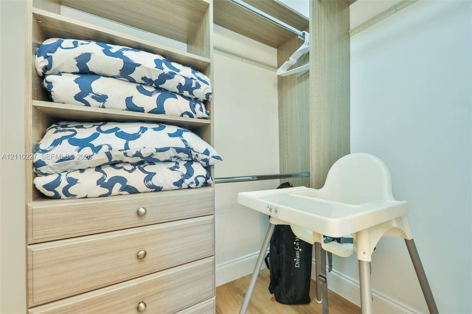 450 Bayshore Drive, Cape Coral, FL 33904 Built-in closet organizer featuring light wood-finish cabinetry, integrated shelving, three lower drawers with round hardware, and a metal hanging rod