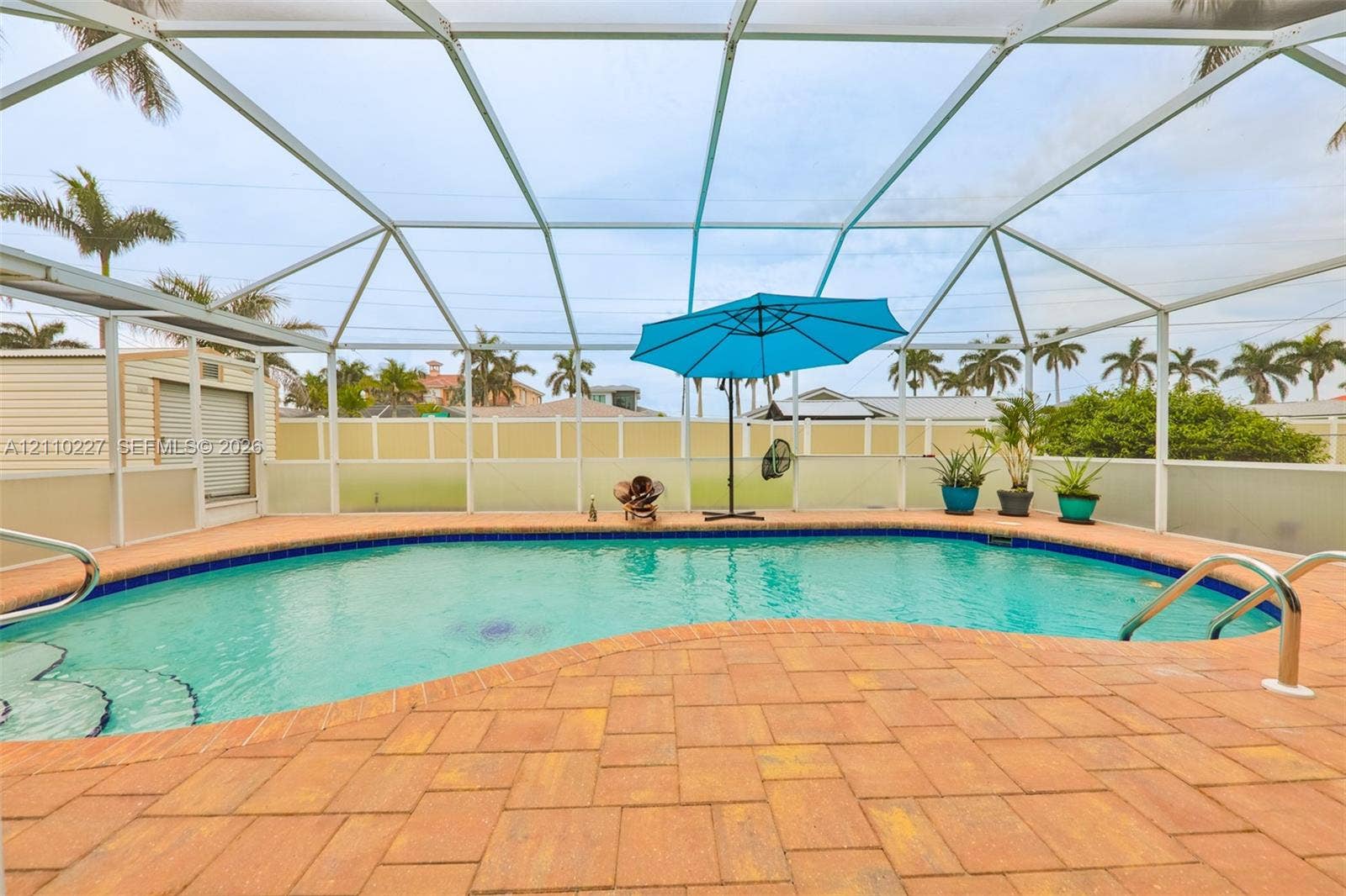 450 Bayshore Drive, Cape Coral, FL 33904 Screened-in outdoor living space featuring an inground pool with paver decking and metal handrails