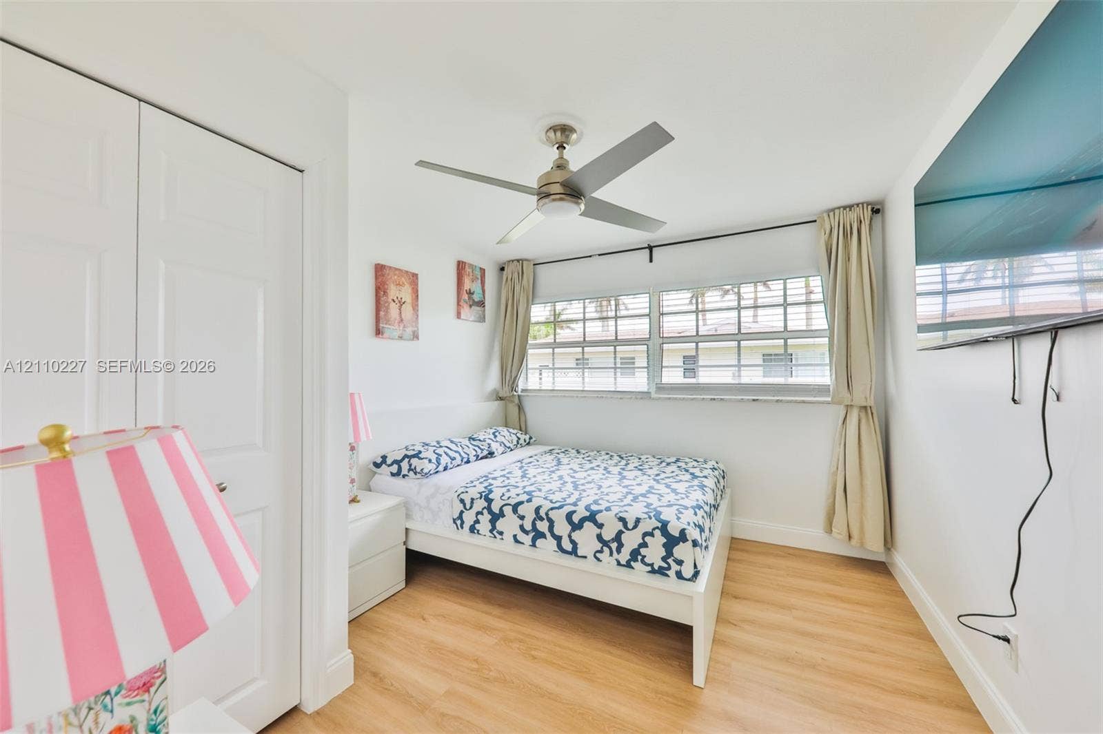 450 Bayshore Drive, Cape Coral, FL 33904 Light-filled room featuring wood-finish flooring, a multi-blade ceiling fan, multi-pane windows, and dual-panel closet doors