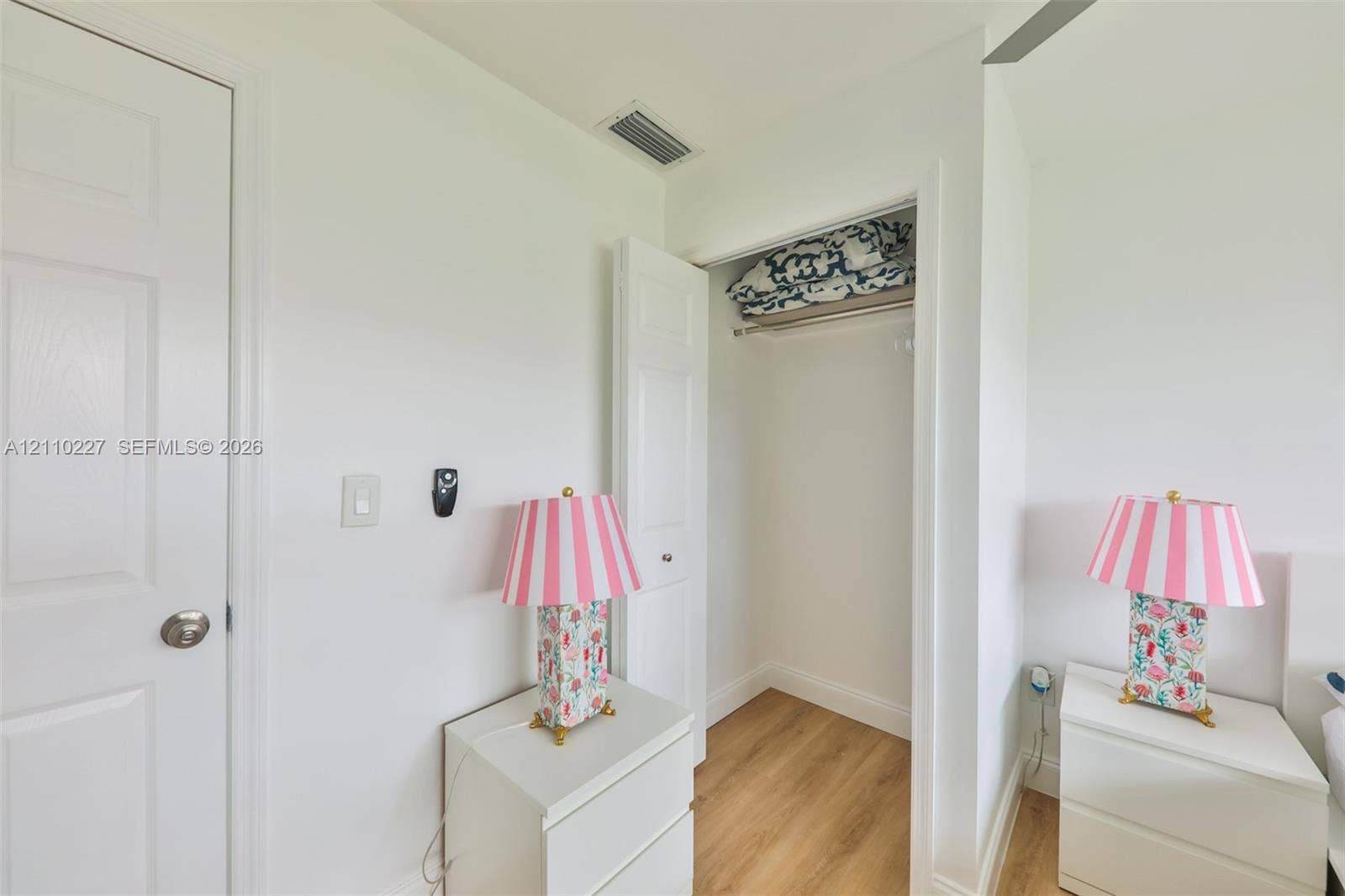 450 Bayshore Drive, Cape Coral, FL 33904 Interior space featuring wood-finish flooring, a reach-in closet with integrated shelving and hanging rod, and a multi-panel interior door