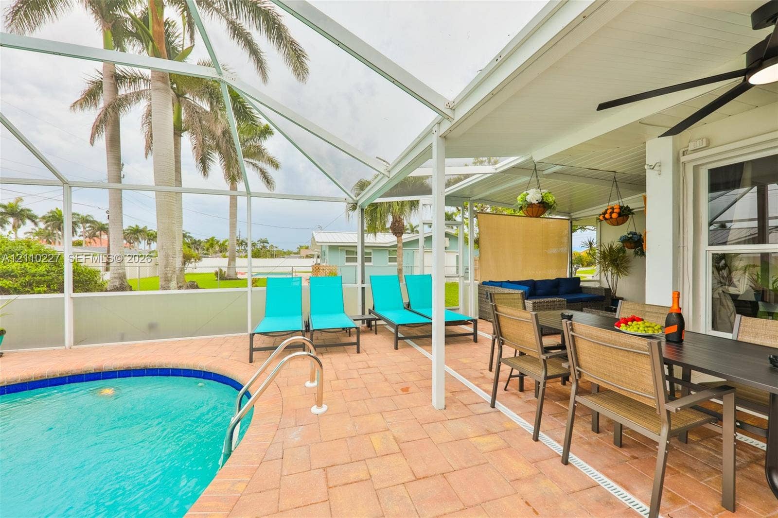 450 Bayshore Drive, Cape Coral, FL 33904 Screened outdoor living area featuring a paved pool deck, swimming pool with perimeter tiling, covered patio, and ceiling fan