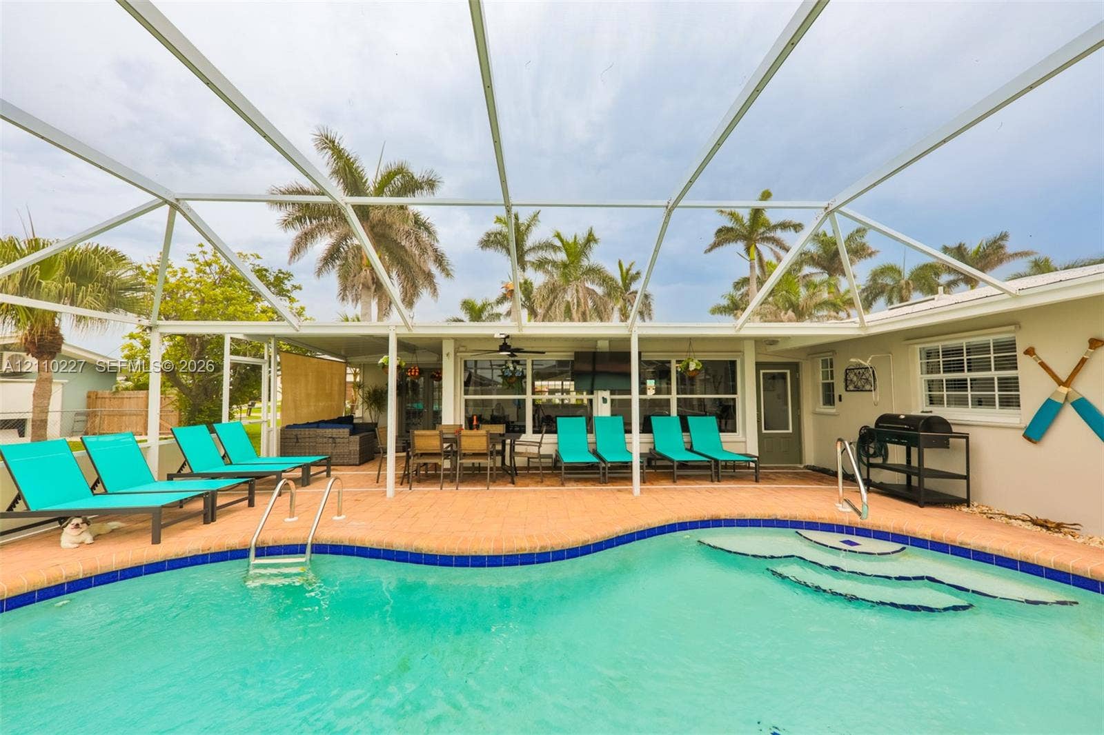 450 Bayshore Drive, Cape Coral, FL 33904 Screen-enclosed patio area featuring a paver deck, built-in swimming pool with step entry, and a ceiling fan