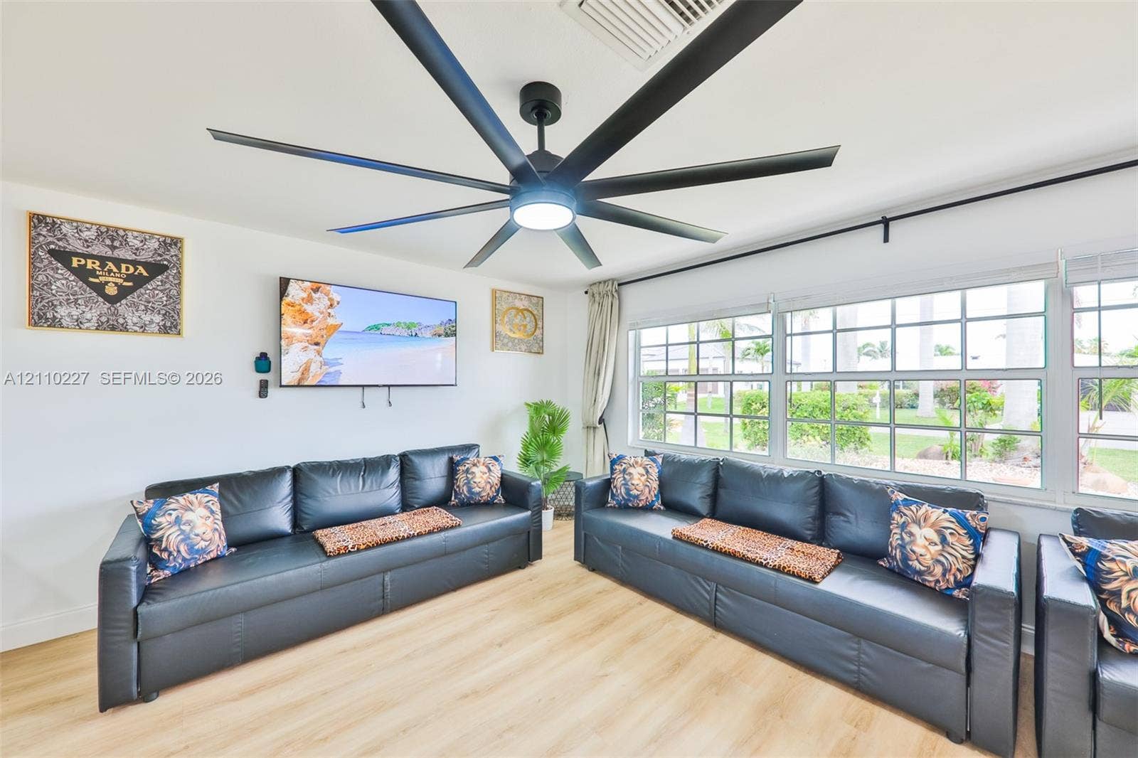 450 Bayshore Drive, Cape Coral, FL 33904 Multi-blade matte black ceiling fan with integrated lighting, wood-finish flooring, and expansive grid-pane windows