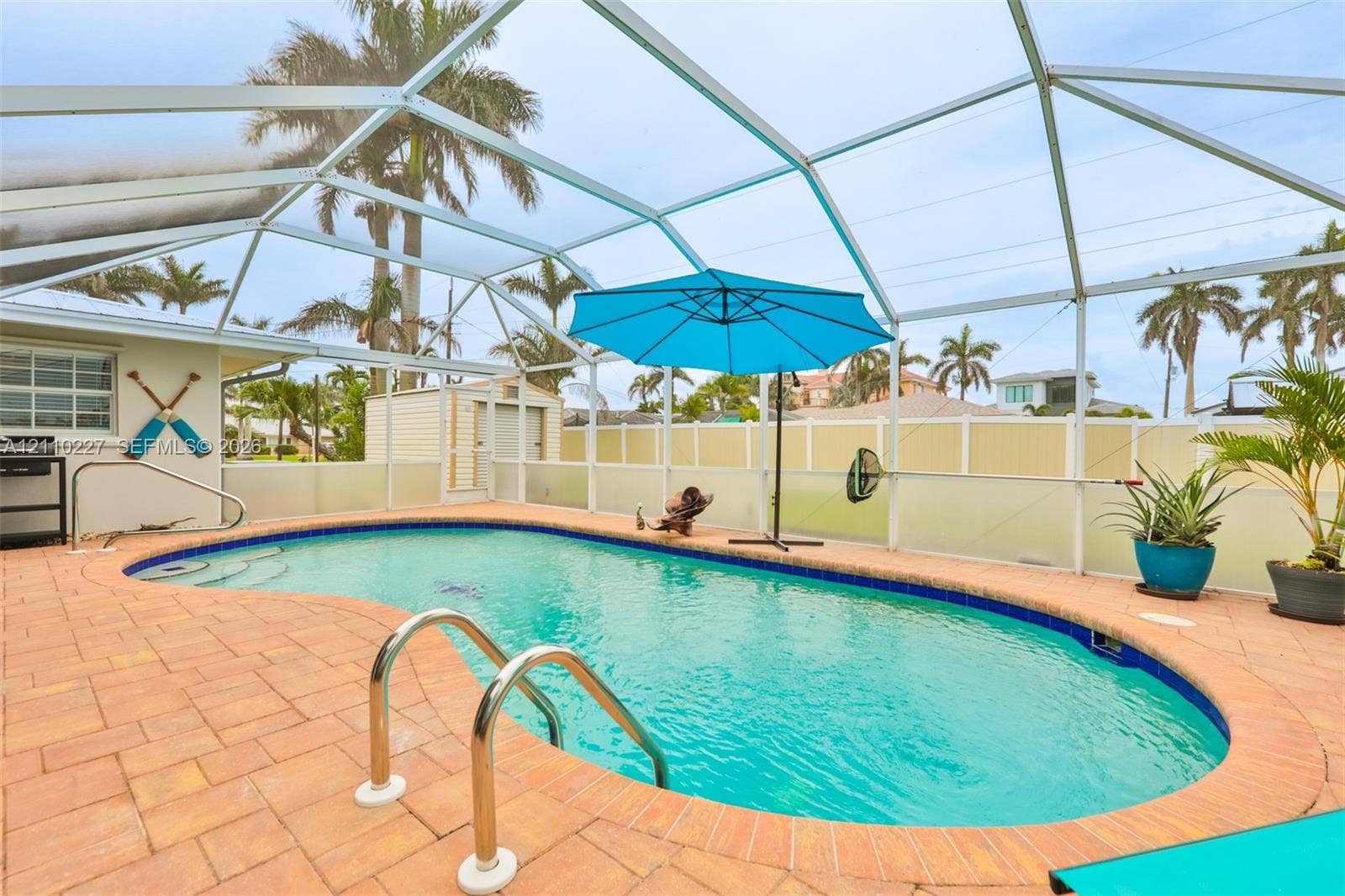 450 Bayshore Drive, Cape Coral, FL 33904 Screened-in patio featuring a kidney-shaped swimming pool, paver deck, and perimeter fencing