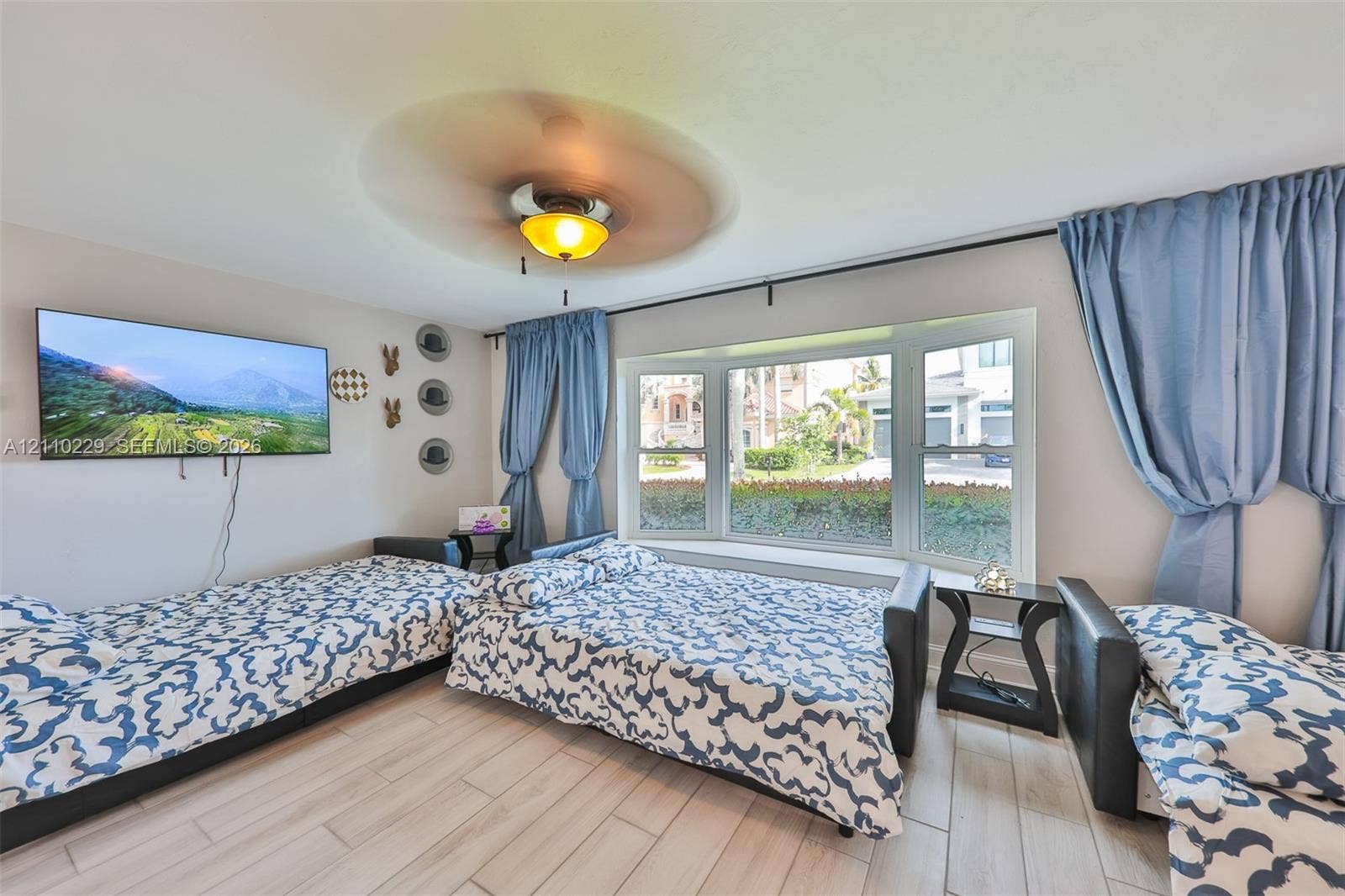 Bay window, wood-finish tile flooring, and ceiling fan with integrated lighting