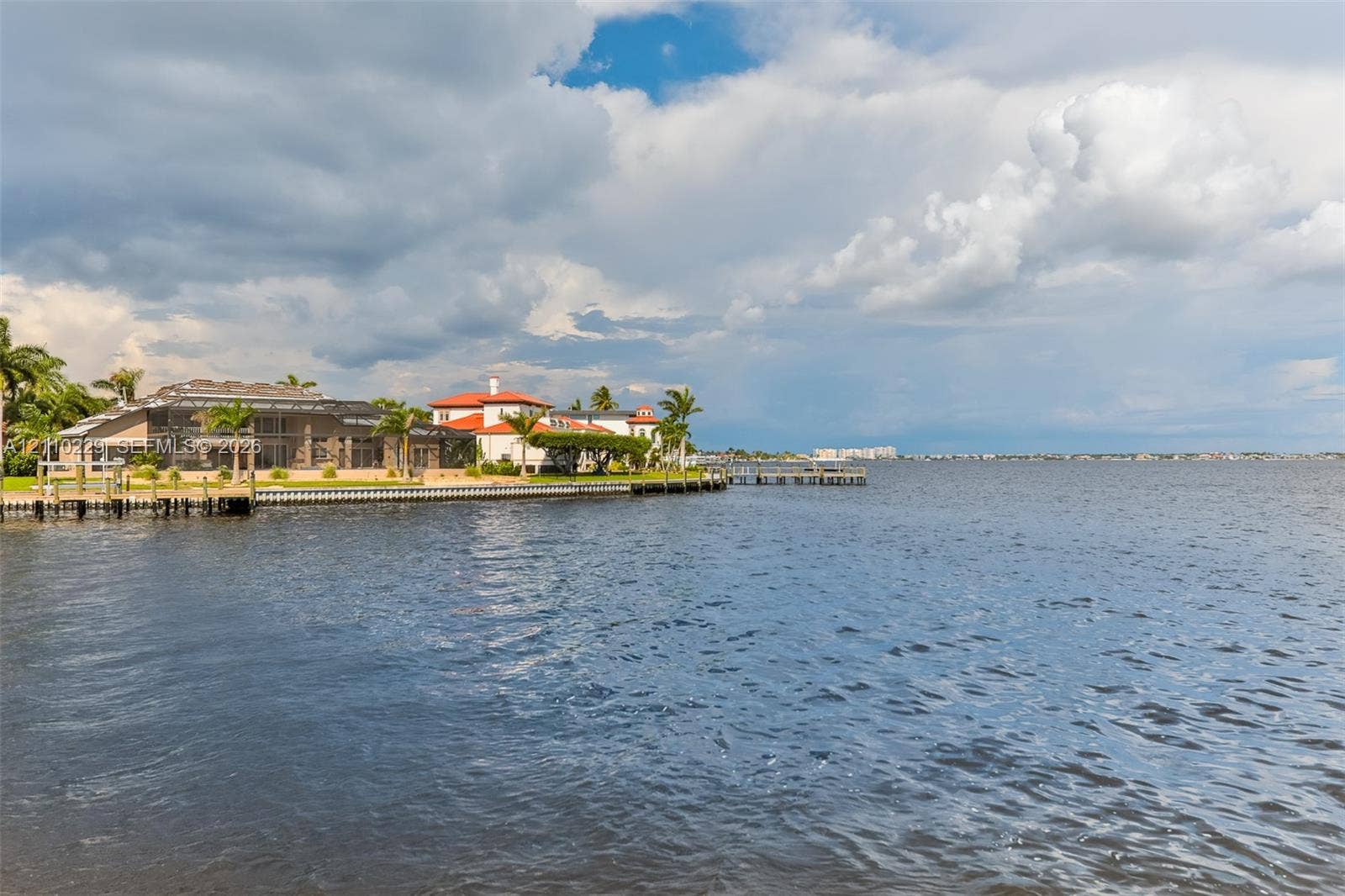 Waterfront property featuring a private dock, bulkhead, and multi-story residence with a tile roof