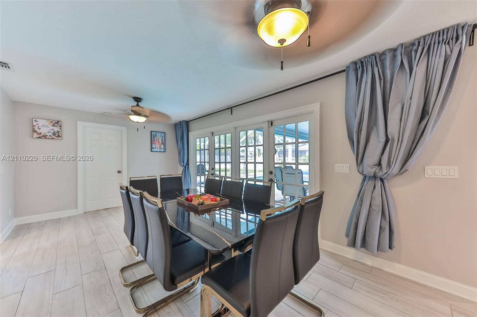 Wood-finish flooring, ceiling fans, and multi-panel glass doors with paneled grid detailing