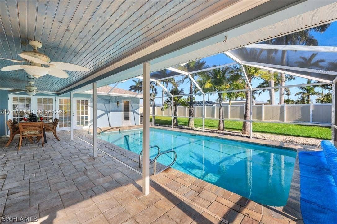 Screened-in pool area featuring paver decking, tongue-and-groove ceiling, and ceiling-mounted fans