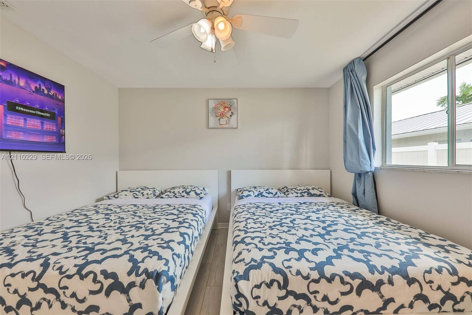 Bedroom featuring wood-finish flooring, a multi-light ceiling fan, and a single-hung window with a neutral stone sill
