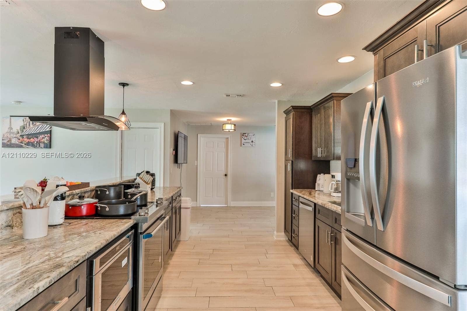 Kitchen featuring stone countertops, stainless steel appliances, dark wood cabinetry, recessed lighting, and tile flooring