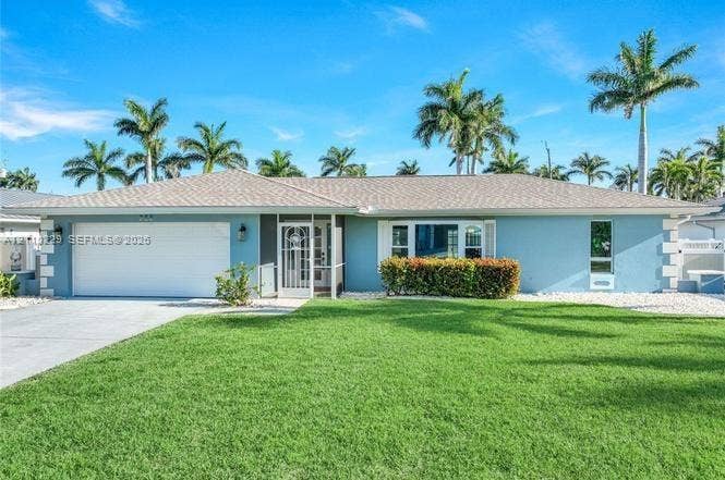 Single-story residence featuring a light-toned exterior, concrete driveway, two-car garage, manicured lawn, and mature palm trees