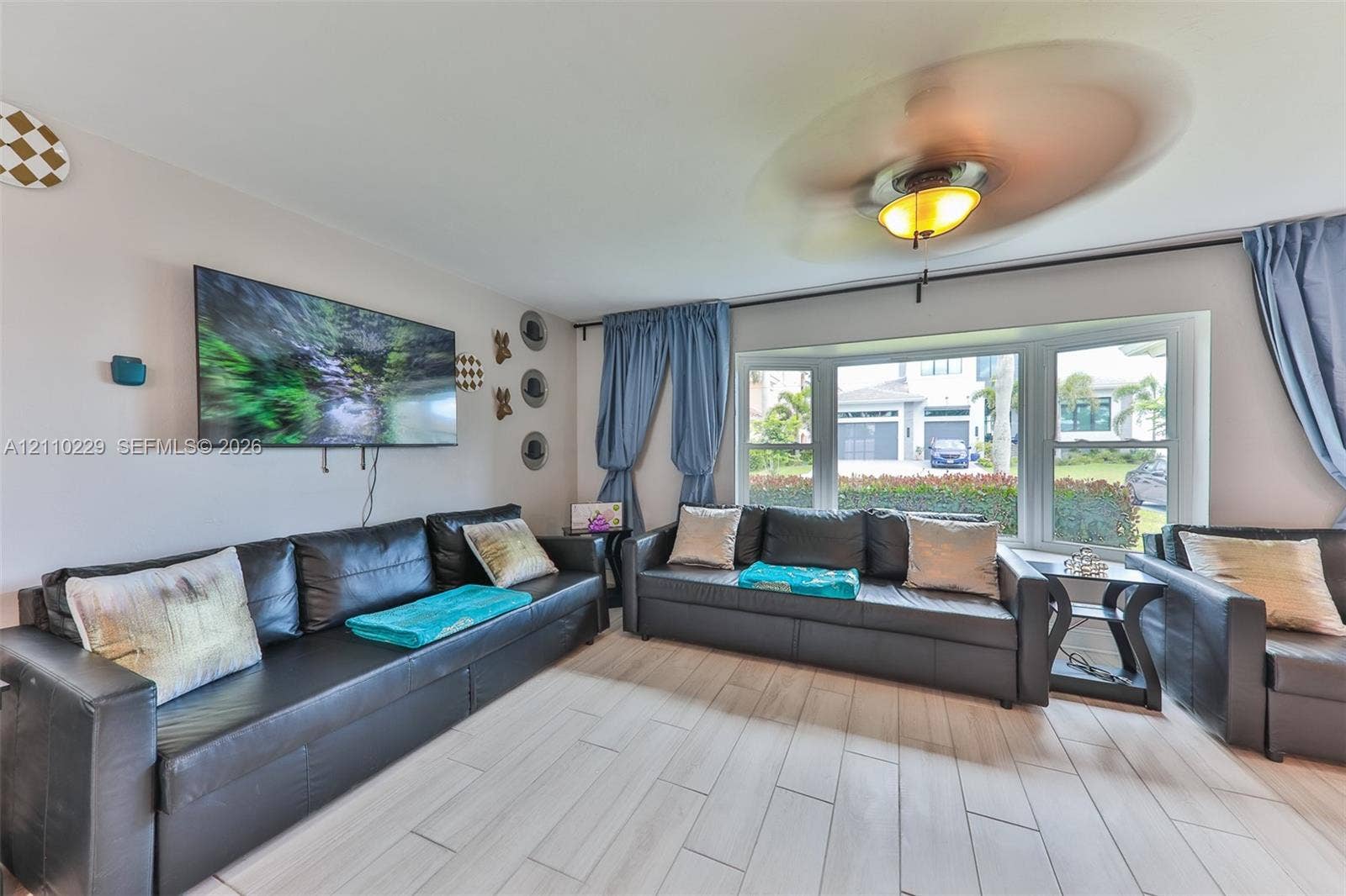 Large bay window providing natural light, neutral wall palette, and wood-finish tile flooring