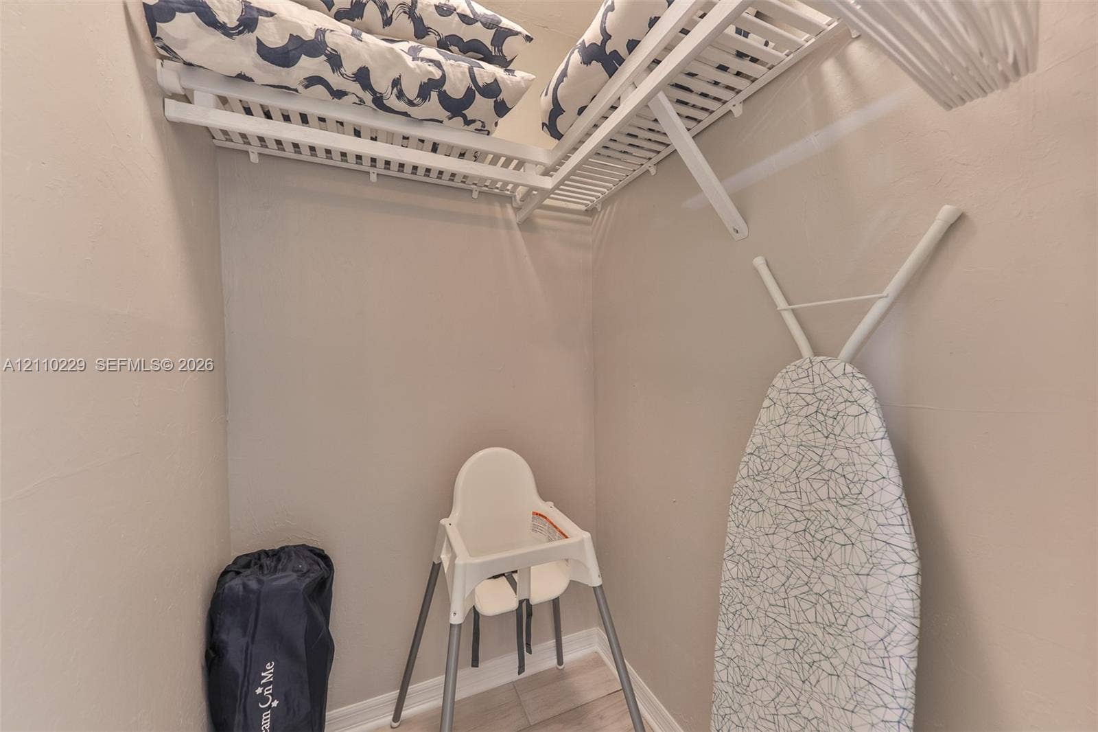 Storage area featuring white ventilated shelving and light-toned tile flooring