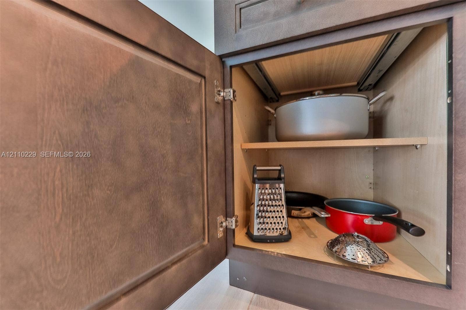 Stained wood cabinetry featuring a recessed panel door, adjustable shelving, and a built-in sliding drawer mechanism