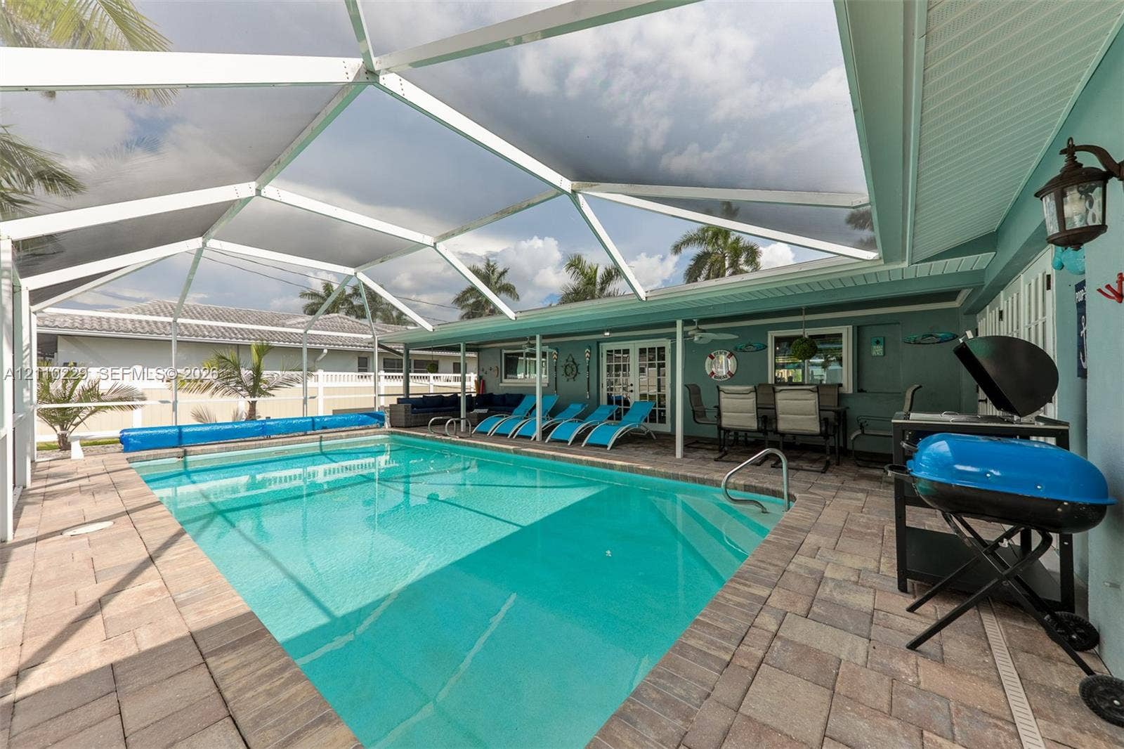 Screened lanai featuring a swimming pool, stone-paver decking, and a ceiling fan