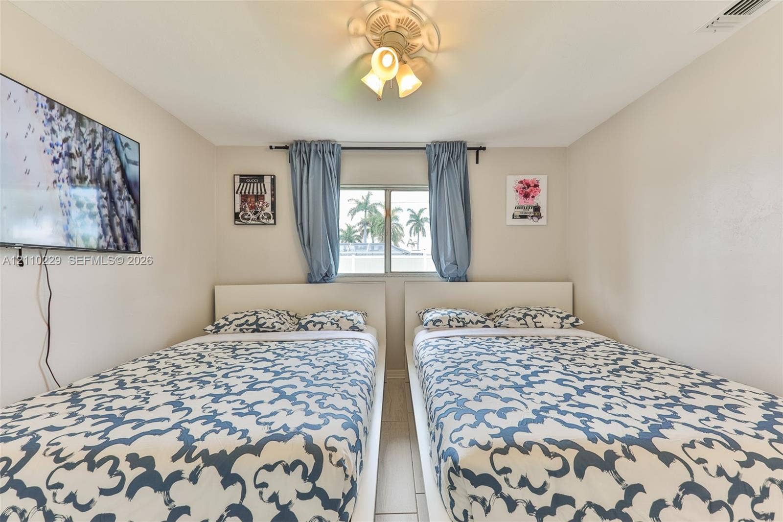 Neutral wall finish, tiled flooring, centered window with dual drapery panels, and a three-light ceiling fixture