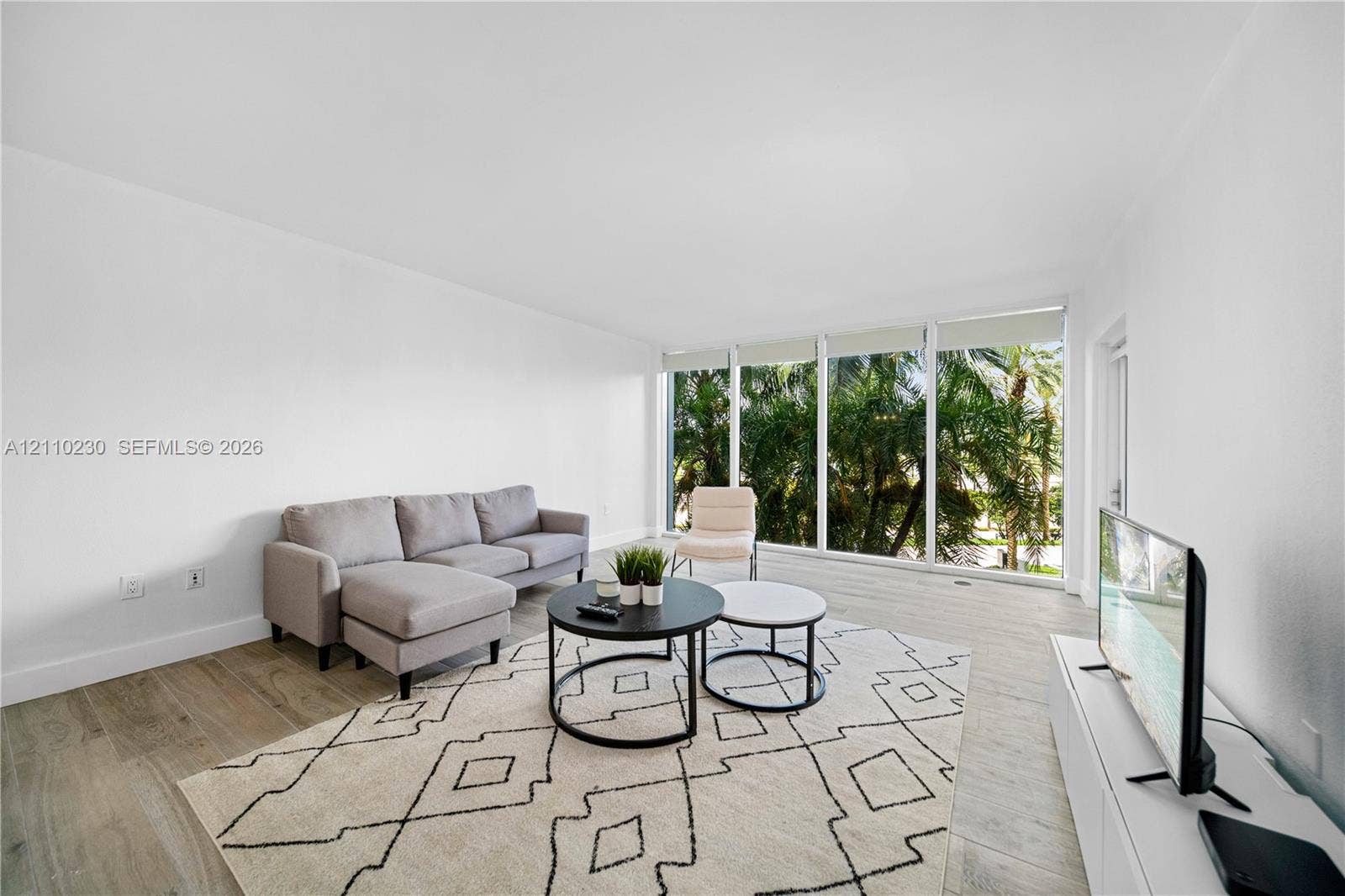 Expansive living area featuring floor-to-ceiling windows, wood-finish flooring, and neutral wall tones