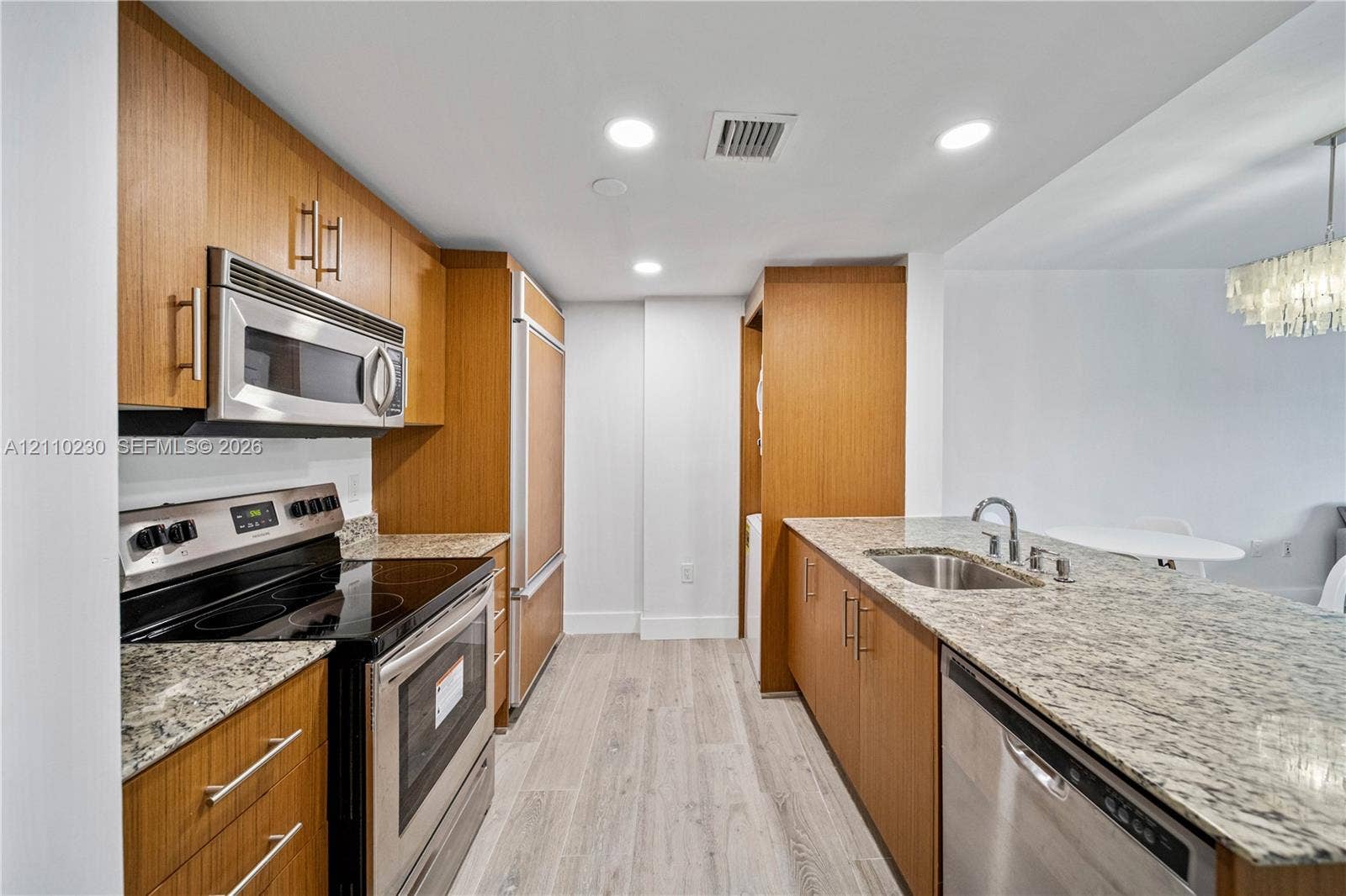 Kitchen featuring natural wood-finish cabinetry, stone countertops, stainless steel appliances, and wood-finish flooring