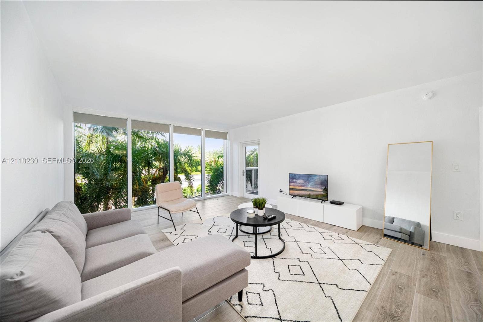 Living area featuring wood-finish flooring, floor-to-ceiling windows, and glass-paneled entry door