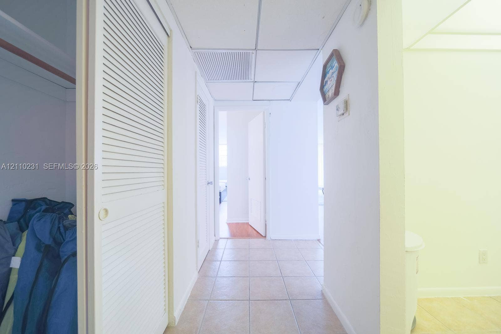19370 Collins Avenue, #622, Sunny Isles Beach, FL 33160 Hallway featuring ceramic tile flooring, bi-fold louvered closet doors, and a suspended drop ceiling