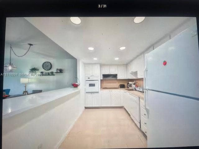 19370 Collins Avenue, #622, Sunny Isles Beach, FL 33160 Kitchen featuring white cabinetry, solid-surface countertops, built-in wall oven, recessed ceiling lighting, and a peninsula with counter seating